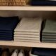 Pantalones doblados por colores en pilas bajas dentro de una balda.