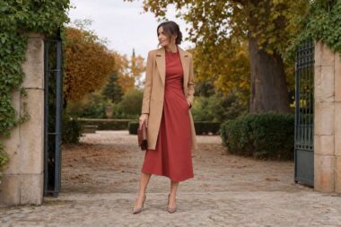 Invitada con vestido color teja y abrigo camel en una finca otoñal.